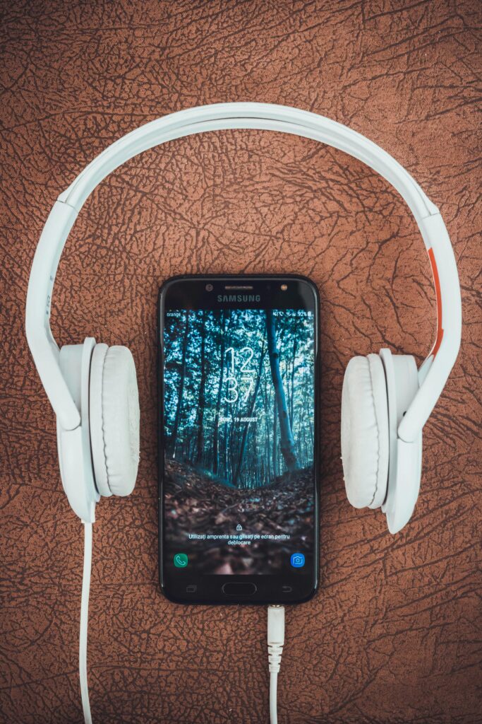 A smartphone paired with white headphones on a brown textured surface, capturing modern tech vibes.